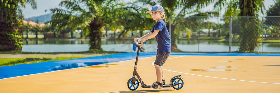 横幅，长格式 快乐的孩子骑着滑板车在篮球场上。
