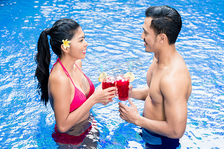 亚洲夫妇在泳池里喝酒