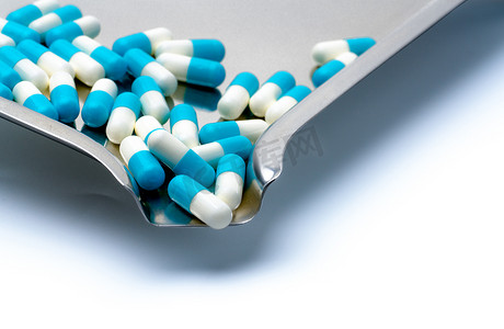 蓝色和白色胶囊药丸和药物托盘在白色背景与文本复制空间。