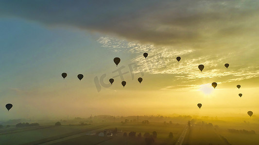 许多热气球在清晨飞入阳光和薄雾中的鸟瞰图
