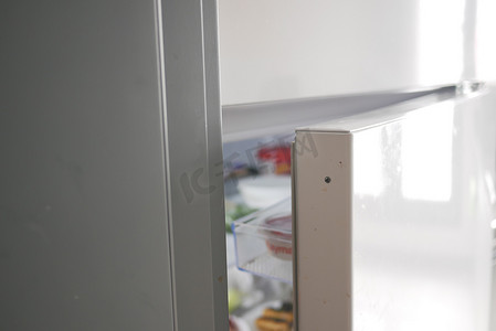 开电动摄影照片_半开冰箱，里面有食物和蔬菜，