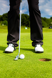 洞阳光摄影照片_高尔夫球手将球放入洞中