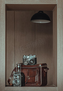 老式两镜头相机上的沙漏、复古怀表、老式棕色皮包上的老式胶片相机、方形木框内部。