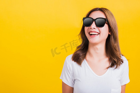 女人的侧脸摄影照片_戴着墨镜、看着侧面的女人快乐地微笑着洁白的牙齿