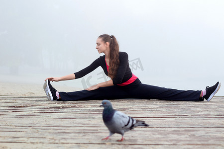 年轻的运动女孩在户外健身锻炼时伸展身体