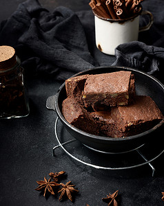 在木桌上的黑色金属煎锅中烤制的巧克力布朗尼蛋糕和核桃，俯视