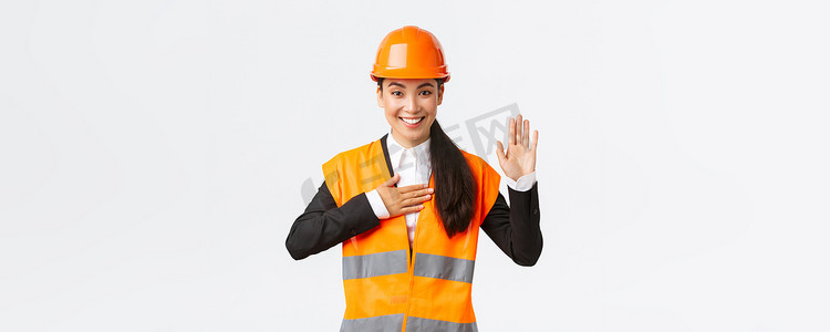 真诚、诚实、自信的亚洲女工程师在建筑区，做出承诺，向客户宣誓，看起来值得信赖，站在安全帽上，说真话，白色背景