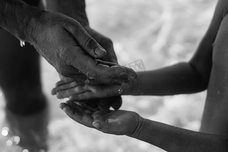 男人把水滴递给孩子的手，握住在张开的手掌上舀出液体。
