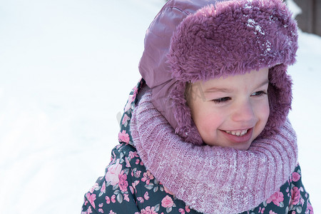 冬天、家庭、童年概念 — 特写肖像真实的学龄前未成年 3-4 岁小女孩戴着粉红色的帽子，看着镜头在雪天里微笑。