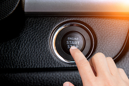 手指按下汽车上的启动/停止发动机按钮的特写。