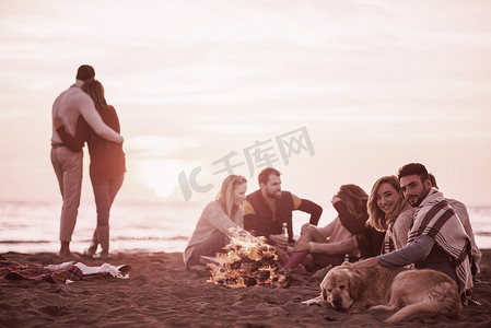 情侣在海滩上与朋友一起享受日落时分
