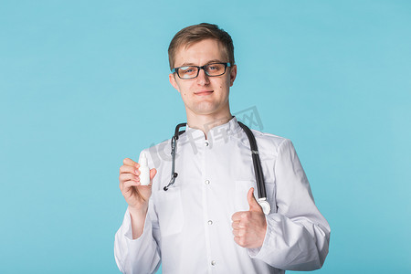 药物和药物概念 — 蓝色背景中竖起大拇指的男医生或药剂师拿着鼻腔喷雾剂
