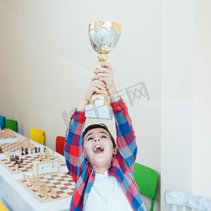 奖杯胜利摄影照片_男孩展示他在国际象棋比赛中赢得的奖杯