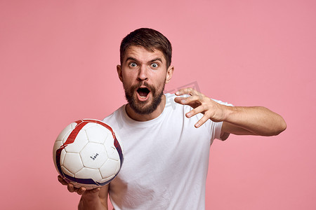 在粉红色背景能量上拿着足球的男人用他的手教练情绪模型指手画脚