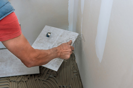 工人将瓷砖粘合剂应用于铺设瓷砖的地板过程