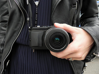 手机胶套摄影照片_女人手里拿着皮套里的旧复古胶片单反相机