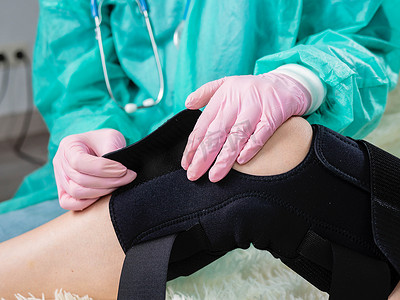 物理治疗师帮助女性在腿部手术后戴上支架。