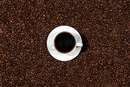 咖啡豆背景上的白咖啡杯的顶部视图