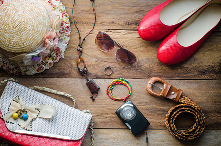 鞋子夏季摄影照片_十几岁女孩度假的配饰、帽子、时尚的夏季太阳镜、皮包、鞋子和木地板上的服装