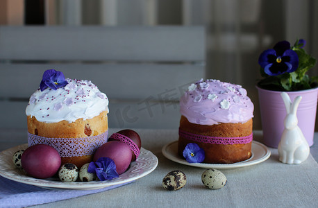 复活节静物画、复活节蛋糕、鸡肉和鹌鹑蛋，在紫罗兰色和灰色纺织品背景上。