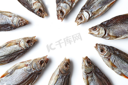 小鱼干摄影照片_生涩的或干的咸鱼排成圆圈，白色背景中突显出美味的小鱼。