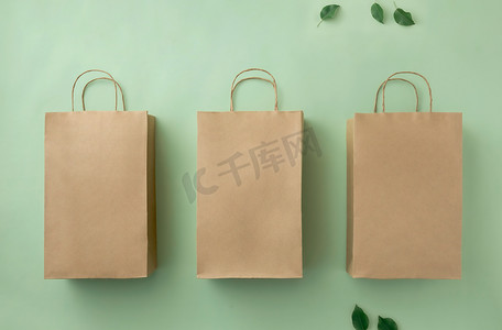 绿色生态背景和绿叶上的三个纸板牛皮纸袋。