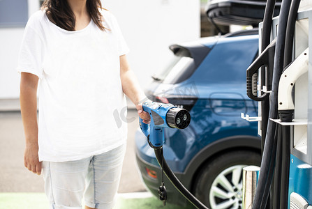 女人在加油站给电动汽车充电。