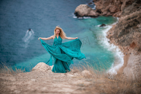身着翡翠裙的女子，长着丝绸长翅膀的时装模特，飘逸的长裙，飞舞的布料在堤岸上。