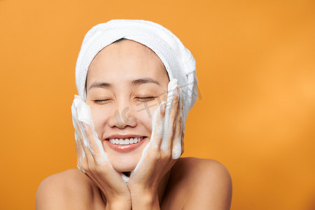 脸上的泡沫摄影照片_年轻的亚洲女性在脸上涂抹保湿霜。