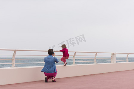海边长廊上的妈妈和可爱的小女孩