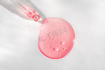 白色背景上带有粉红色液体透明质酸的吸管。