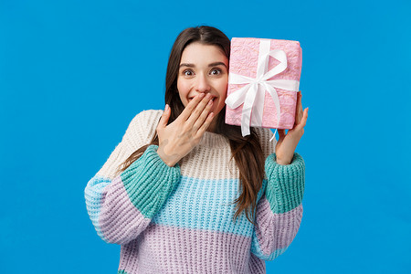 快乐开朗的可爱女孩猜盒子里装的是什么，收到礼物时面带微笑，又惊又喜，不敢相信男朋友买了她想要的圣诞假期，收到了很棒的礼物