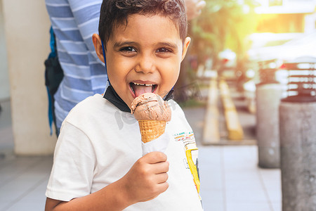 暑假期间在购物中心享用冰淇淋的拉丁男孩，脸色淘气
