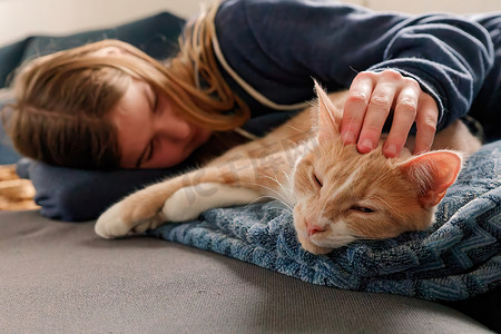 一个躺在沙发上的年轻少女通过依偎和抚摸她的猫来找到​​安慰