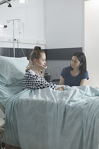 坐在儿科诊所康复病房里，紧张不安的父母与受伤生病的小女儿交谈。