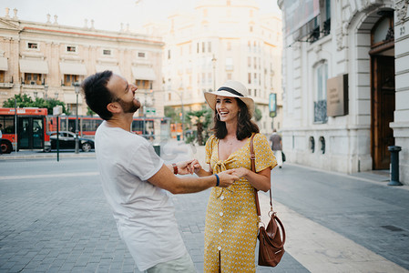在巴伦西亚，一个戴着帽子和裙子的女孩正在和一个留着胡子的男朋友跳舞
