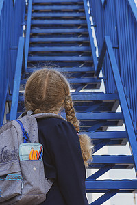 女学生抬头看楼梯.. 穿着制服背着背包的女孩。