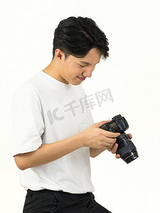 亚洲摄影师站在白色的摄影场景中看着相机屏幕上拍摄的照片。
