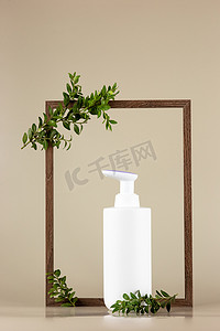 白色化妆品瓶，矗立在一个空木框里，上面有绿色植物的树枝