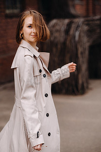 一个穿着灰色外套的快乐时尚女孩在城市里散步