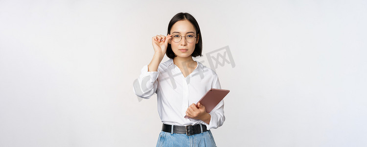 年轻亚洲女商人的形象，戴眼镜的女企业家，拿着平板电脑，戴眼镜看起来很专业，白色背景