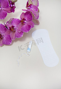 月经期间的卫生用品，卫生棉条或垫子上放一朵紫色的兰花。