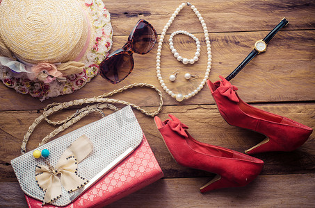少女度假时的配饰、帽子、时尚的夏季太阳镜、皮包、鞋子和木地板上的服装。