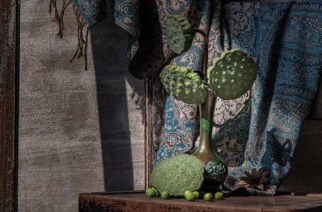 古董雕刻铁壶或旧木椅上的花瓶中的新鲜绿色莲子荚。