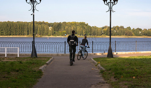 在城市公园的瓷砖路上骑自行车在夏天的日落。