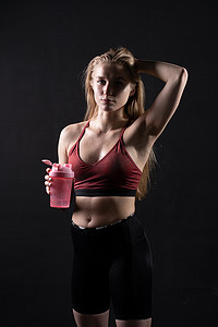 摇床摄影照片_Spotrsman 她的摇床粉红色手里拿着一个穿着黑色背景摇床粉红色黑色锻炼的女孩，在下午的健身房生活方式中，来自年轻和训练运动员，强大的健康。