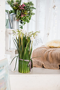客厅时尚现代的波西米亚风格内饰，配有花瓶、米色花边和优雅的水仙、水仙花花束。