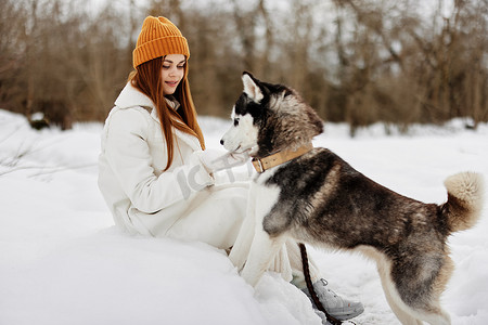 宠物狗玩耍摄影照片_雪地里的年轻女子在户外与狗玩耍友谊寒假