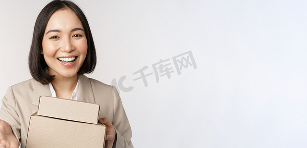 女商人的肖像，亚洲女售货员指着你，给盒子下订单，站在白色背景的西装