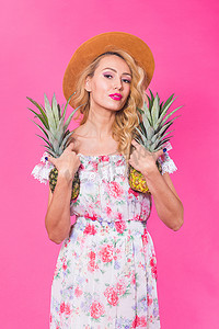 粉色菠萝摄影照片_粉红色背景中带菠萝的年轻美女时尚肖像